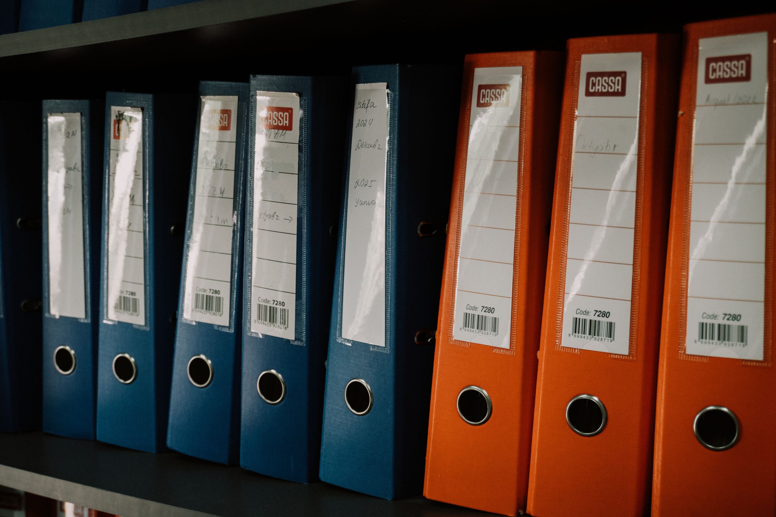 Rangée de classeurs colorés organisés sur une étagère