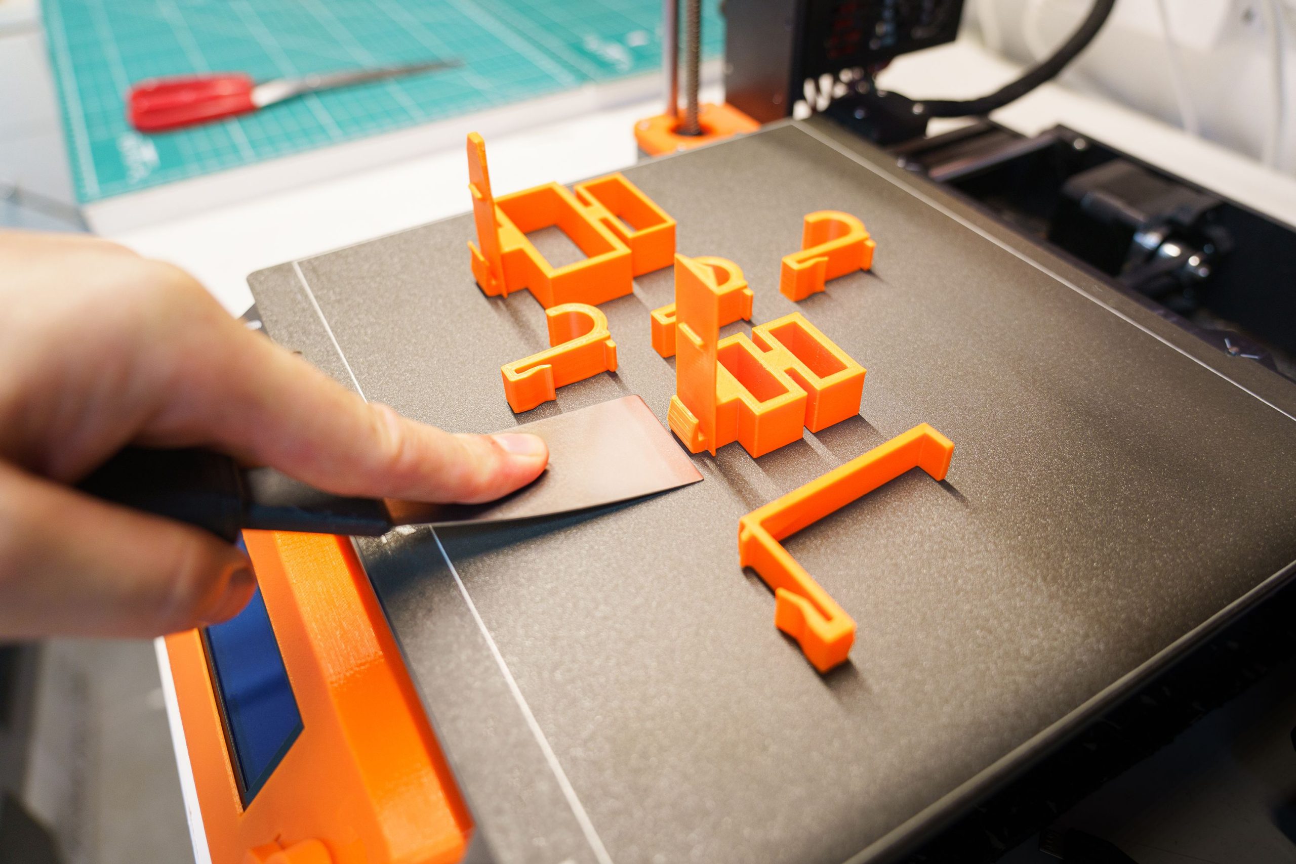 Retrait manuel d'un objet 3D orange du plateau d'impression