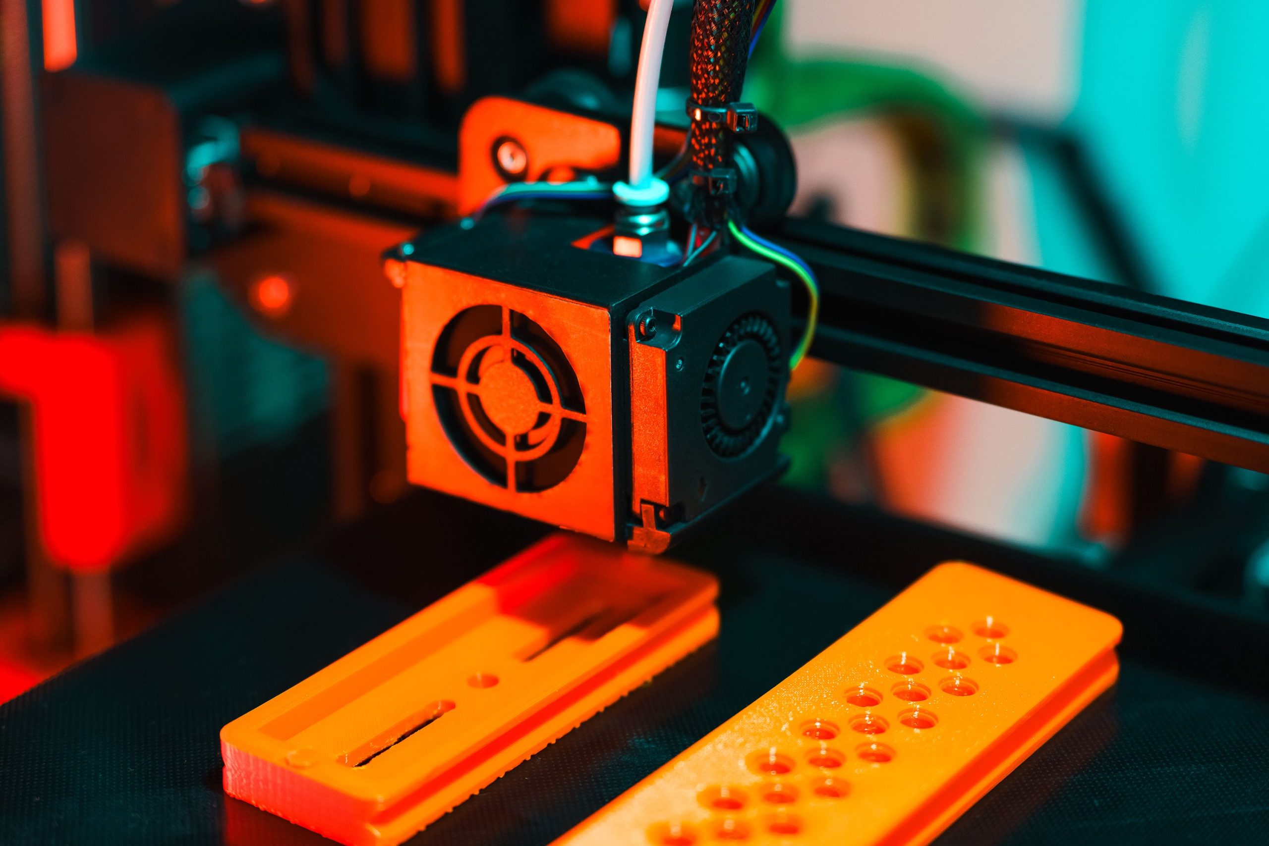 Imprimante 3D en action extrudant des composants plastique orange