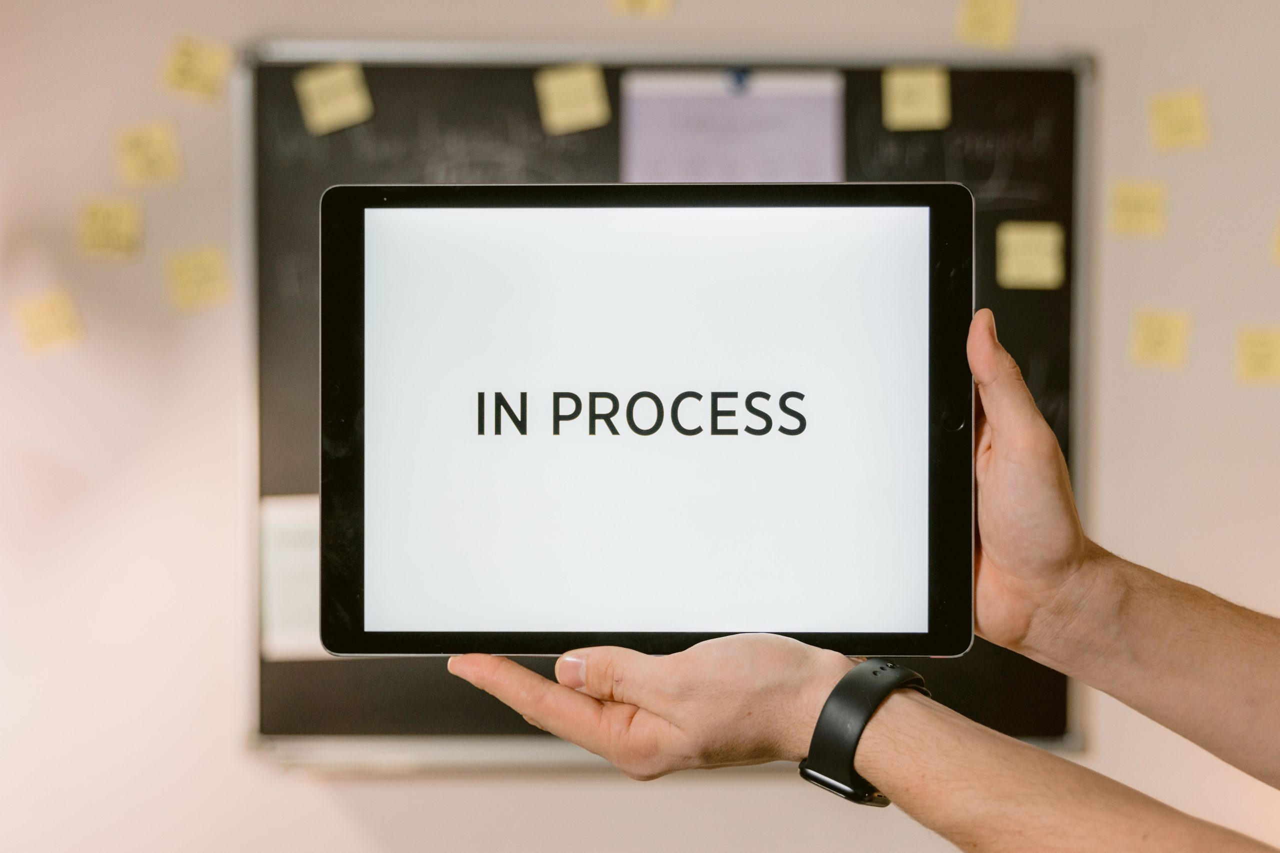 Mains tenant une tablette affichant le statut en cours