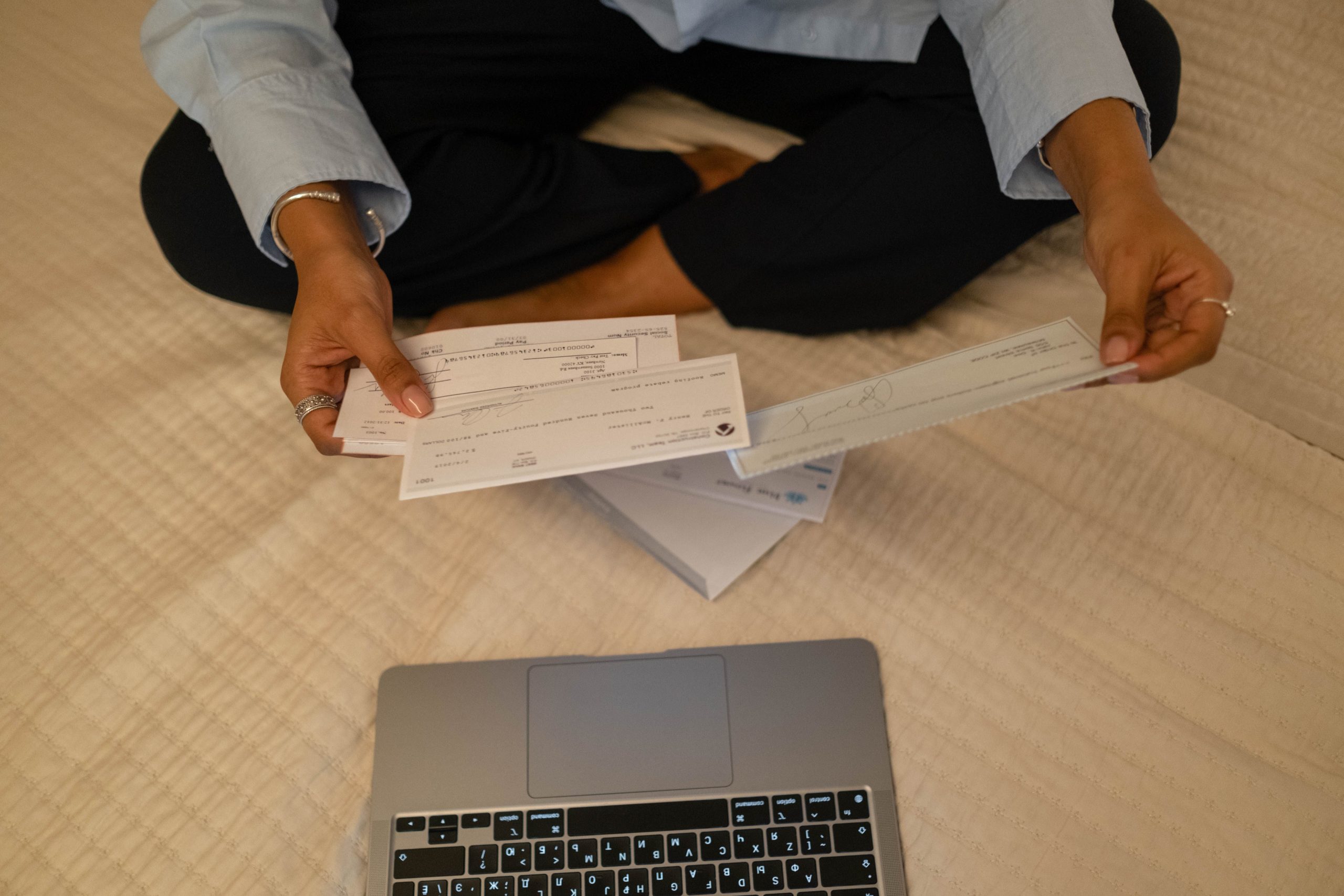 Mains tenant des chèques près d'un ordinateur portable