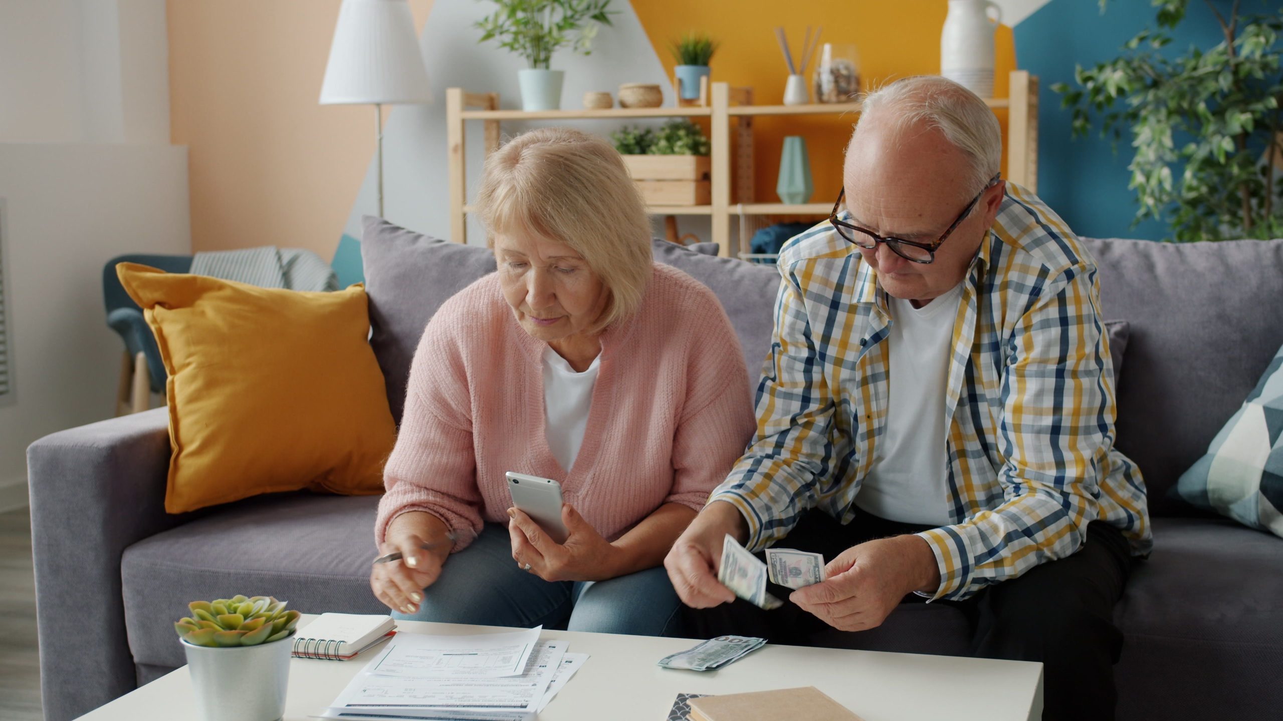 Couple senior budget canapé smartphone argent