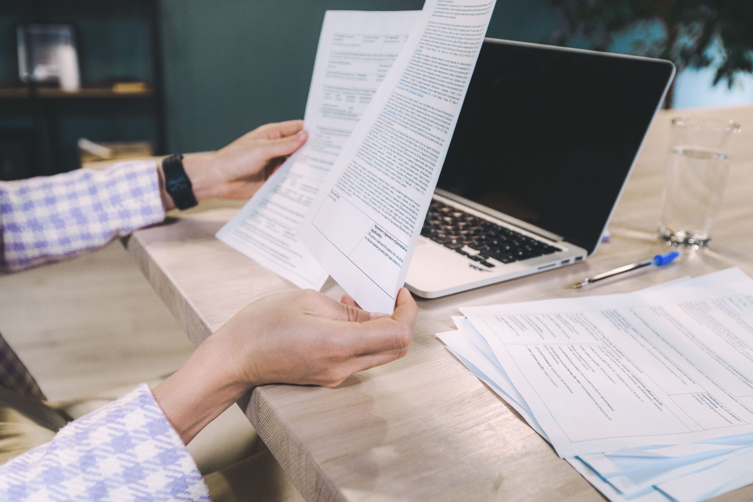 Mains examinant documents imprimés près ordinateur
