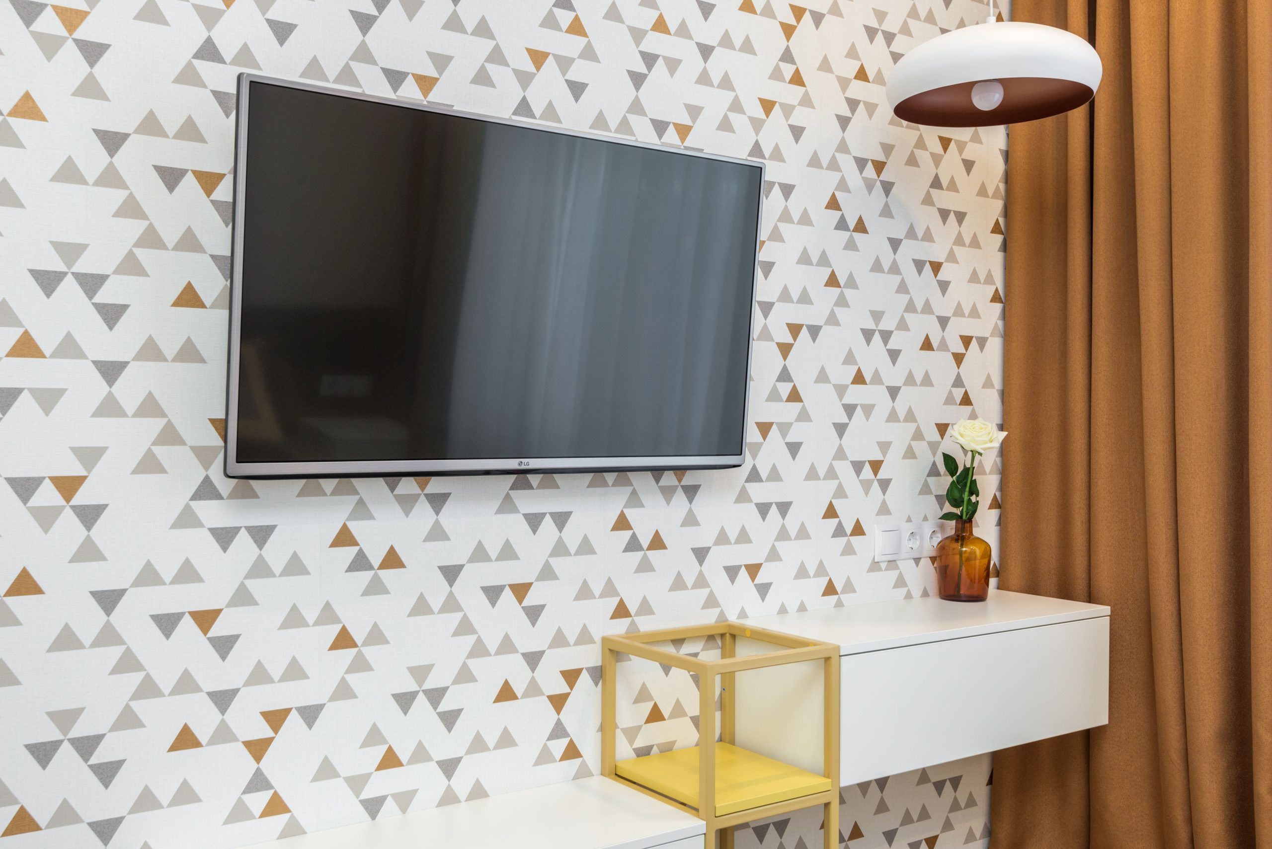 Chambre élégante avec télévision et papier peint géométrique