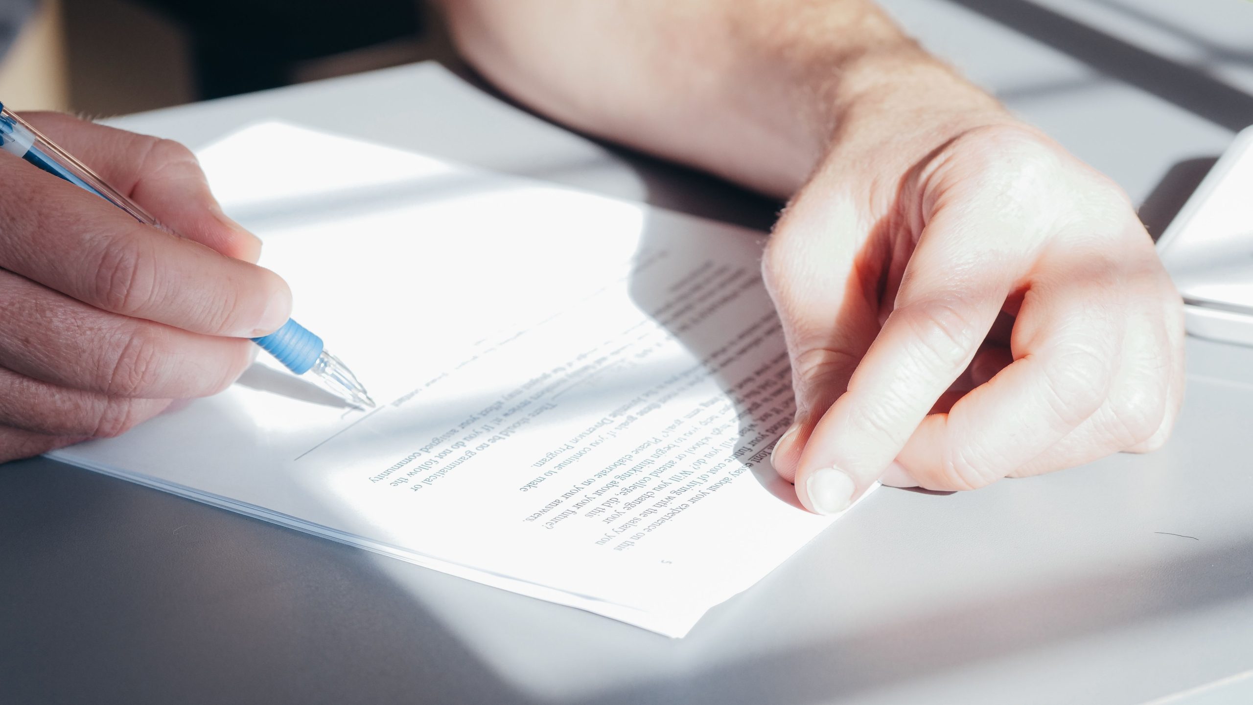 Mains signant un contrat avec un stylo bleu
